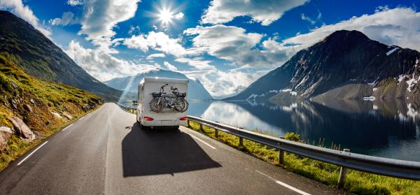 Wohnmobil mit Fahrrädern fährt entlang eines Bergsees.